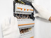 Electrician installing or repairing apartment electrical panel, close-up view