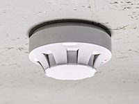 smoke detector of fire alarm on white ceiling at home